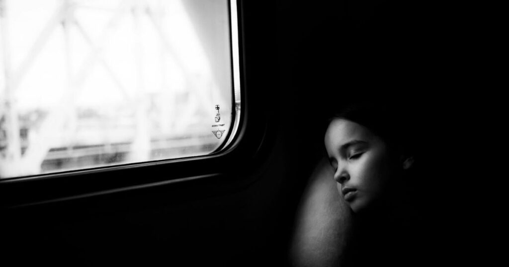 A girl sleeps in a train carriage, illustrating the concept of childhood dreams. 