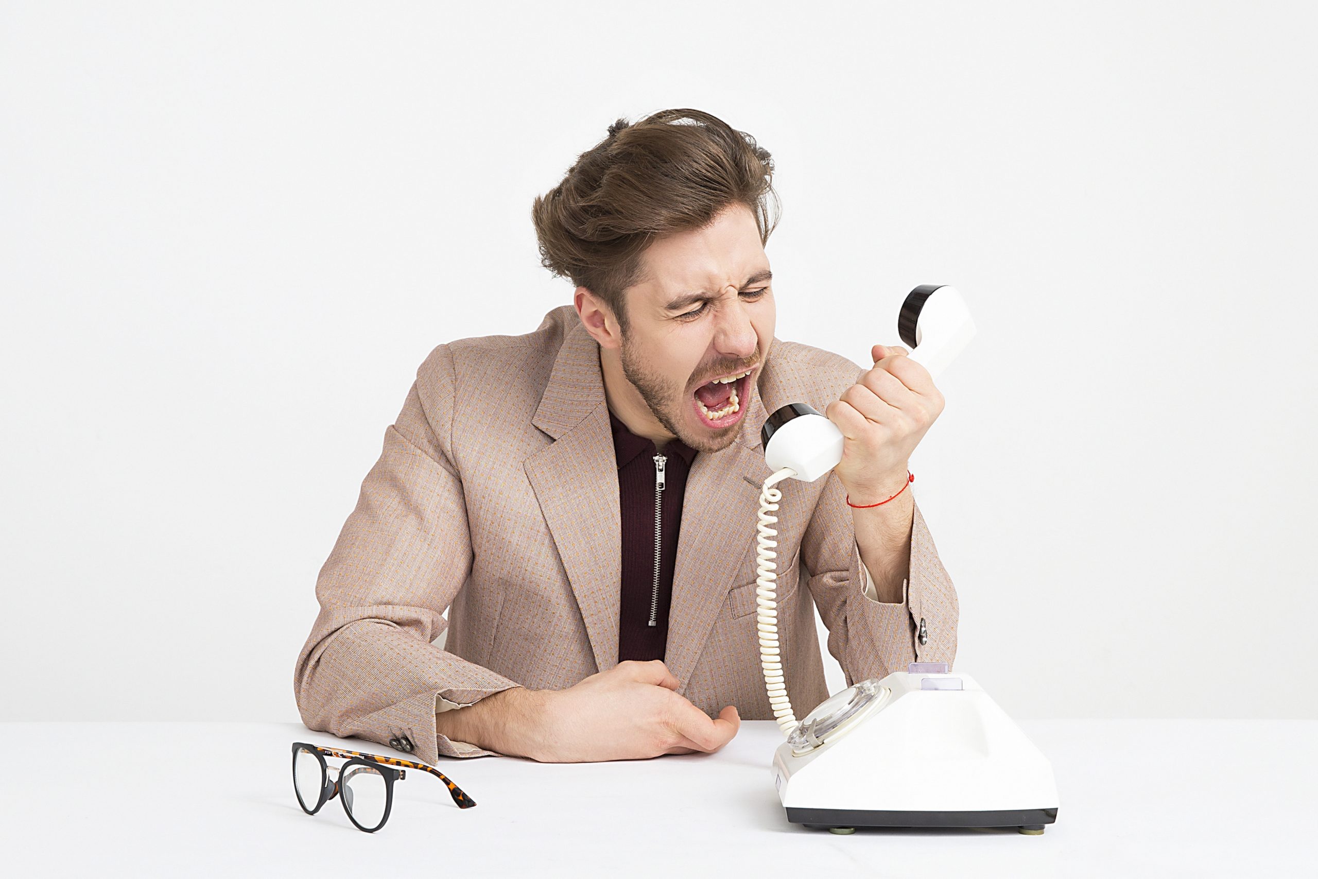 A man shouts into a telephone, illustrating chronic complaining